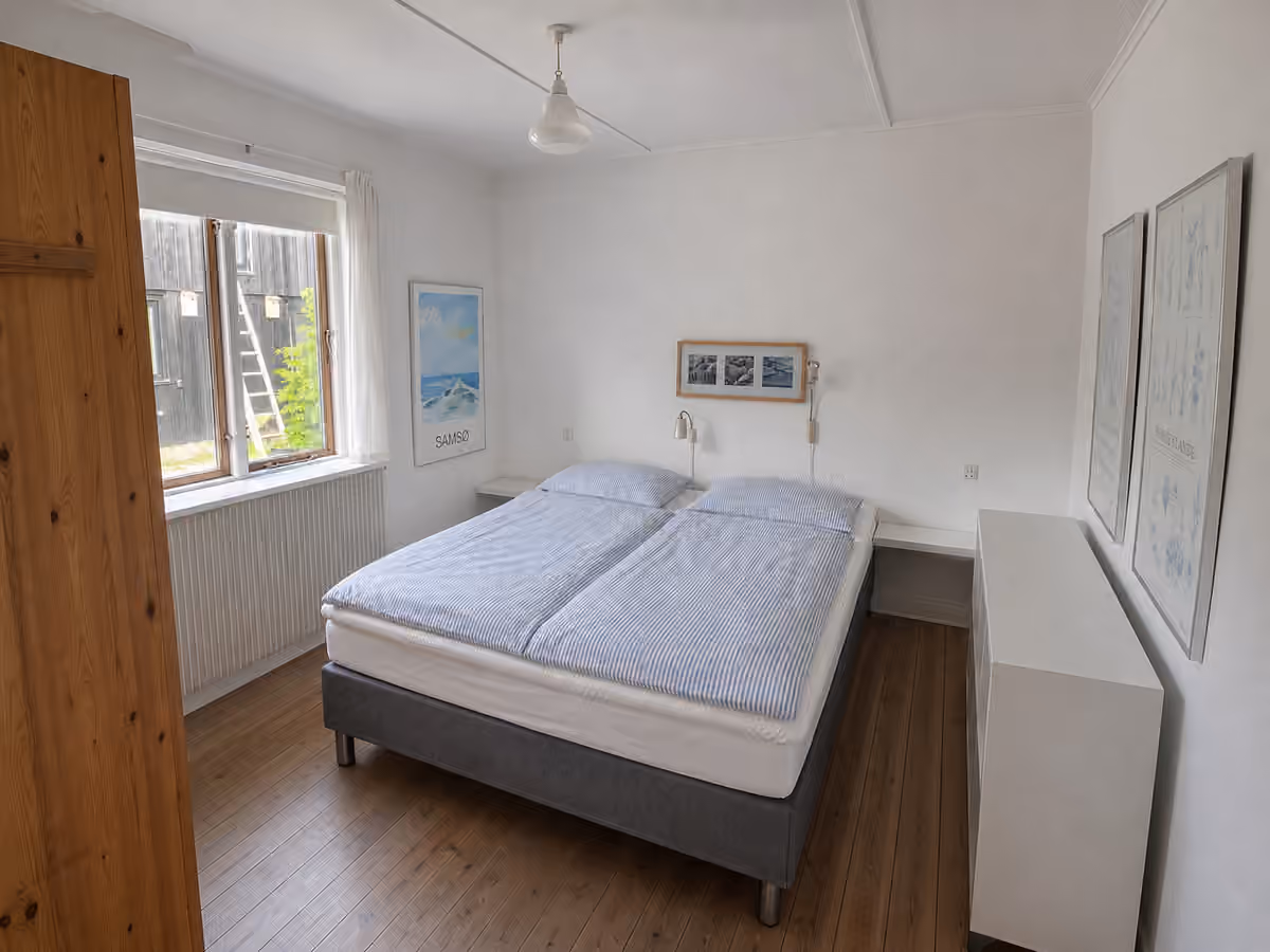 Det ene soveværelse i hovedhuset med en redt dobbeltseng.