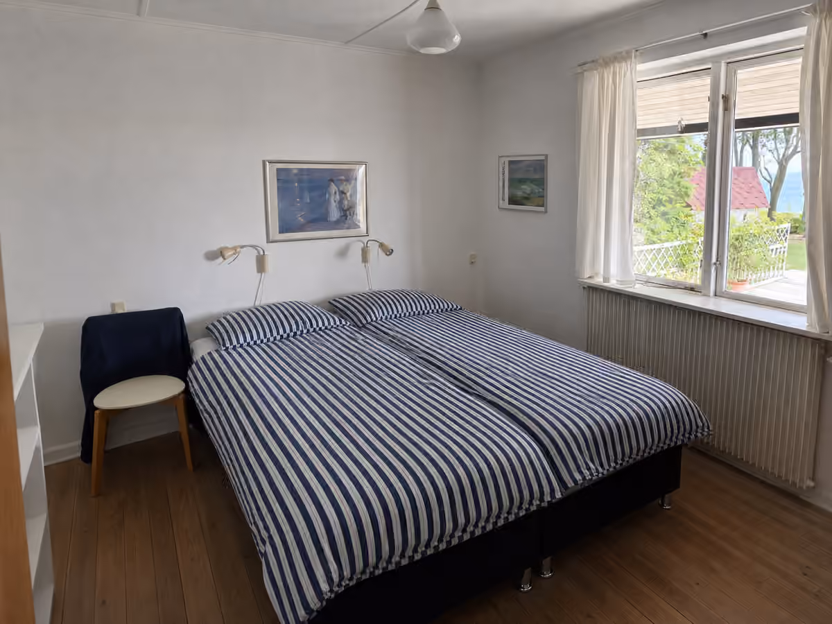 Det andet soveværelse i hovedhuset med en stribet dobbeltseng og havkig.
