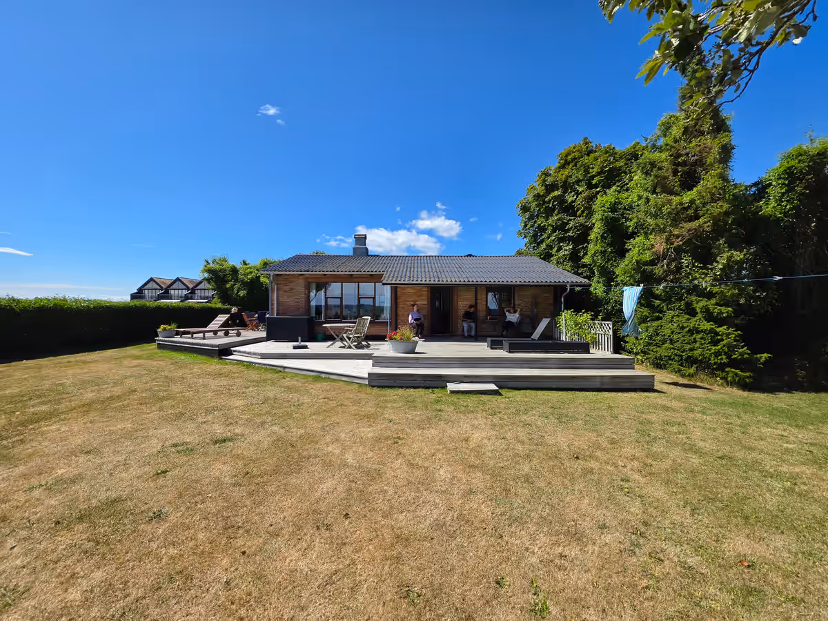 Fassade und Terrasse des Ferienhauses vom Garten aus.